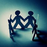 Paper cutout figures holding hands, creating a circle with shadows