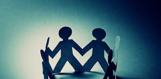 Paper cutout figures holding hands, creating a circle with shadows