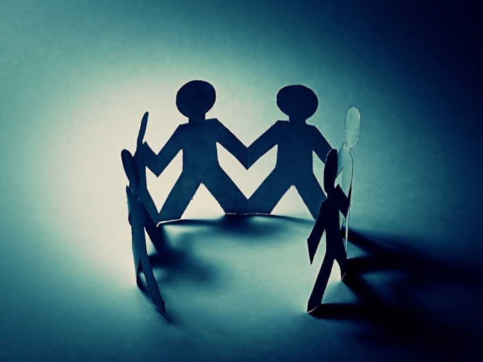 Paper cutout figures holding hands, creating a circle with shadows