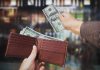 A hand withdrawing cash from a wallet in a blurred background