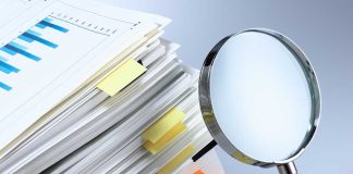 Stack of documents with a magnifying glass beside it