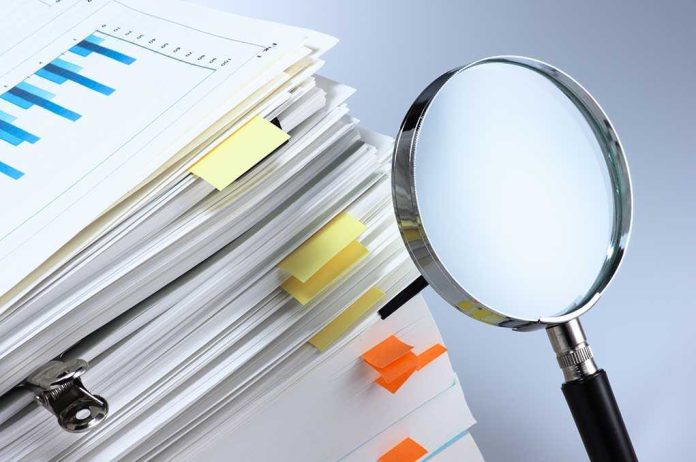 shutterstock_174064394.jpg Stack of documents with a magnifying glass beside it
