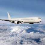 Pilot INJURED in Shocking Mid-Air Collision A white airplane flying above fluffy clouds in a blue sky