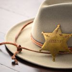 A sheriffs hat with a vintage badge resting on a wooden surface