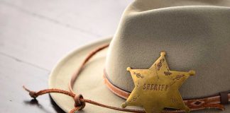 A sheriffs hat with a vintage badge resting on a wooden surface