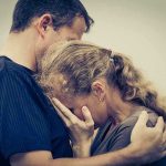 A couple embracing, with one partner comforting the other who is in distress