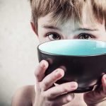 Democrats Accused of Hunger Games Tactics A child with a serious expression holding a bowl close to their face