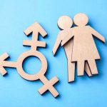 Transgender Sports BOMBSHELL Rocks Maine Schools Wooden transgender symbol and couple figures on blue background.