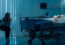 Woman sitting beside hospital bed at night.