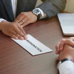 Handing in a resignation letter across a table.
