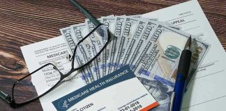 Medicare card glasses pen money on wooden table