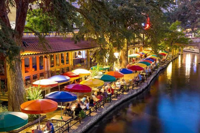 Outdoor riverside restaurant with colorful umbrellas and evening lights.