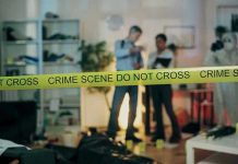 Crime scene with tape and investigators examining evidence.