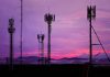 Cell towers against a purple sunset sky.