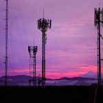 Massive Layoffs: Telecom Industry Shaken Cell towers against a purple sunset sky.