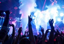 Country Star’s Arrest Shocks Music World Crowd at a concert with hands raised and smoke effects in the background