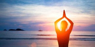 Person meditating on the beach during sunset