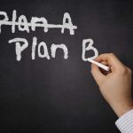A hand writing Plan B on a chalkboard with Plan A crossed out
