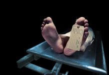 Feet of a deceased person on a coroners table with an identification tag