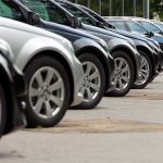 A row of parked black and silver cars in a dealership