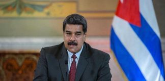 Maduro’s $200 Million Escape Plan EXPOSED Man speaking at podium with Cuban flag in background.