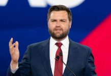 Man in a suit speaking at an event.