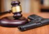 Gavel and handgun on a wooden surface.