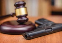 Gavel and handgun on a wooden surface.