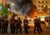 Police Tactics Spark Outrage in New Orleans Police officers in riot gear near burning car.