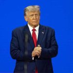 Media Panics As Trump Targets “Enemy Within” Man in a suit with a blue background.