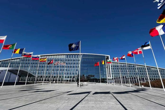 2284120437 Flags outside NATO headquarters building under clear blue sky.