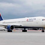 SHOCKING Airline Cover-Up Leaves Passengers Bleeding Delta Airlines airplane on airport runway, cloudy sky.