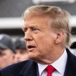 Roger Stone’s FREEDOM – Mueller Probe Doubts Surge Man in suit and red tie speaking outside.