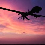 U.S. Weaponizes Iran’s Kamikaze Drone – Unbelievable! Silhouette of a drone against a colorful sunset.