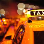Self-Driving Taxi Makes UNREAL 911 Call Close-up of a taxi sign illuminated at night with blurred city lights in the background