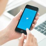 Person holding a smartphone displaying the Twitter app