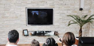 A family of four watching television together in a cozy living room