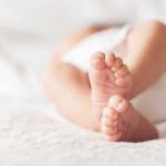 Babies Targeted In Digital ID Sparks Outrage Close-up of baby feet lying on blanket.
