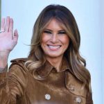 Melania DEMOLISHES Traditional First Lady Playbook Completely Person smiling and waving wearing a brown coat