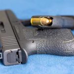 Handgun on blue fabric with visible bullet cartridge.