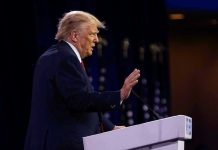 Person speaking at a podium with hand raised