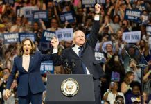 Governor Walz’s Controversial Anne Frank Reference Stuns Two people celebrate on stage with supporters behind.