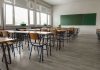 Teacher Blocks ARMED Student With Chair Empty classroom with desks, chairs, windows, and chalkboard.