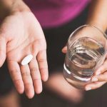 Shocking 11-Year LIFE Expectancy Gap Exposed Person holding pill and glass of water