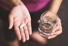 Person holding pill and glass of water
