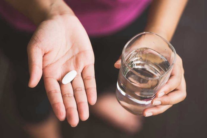 Person holding pill and glass of water