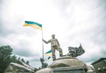 Ukraine Strikes Trigger SHOCKING Border Threat Soldier on tank holding Ukrainian flag.