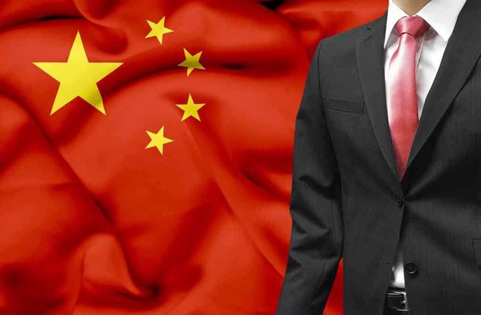A man in a suit stands in front of the Chinese flag