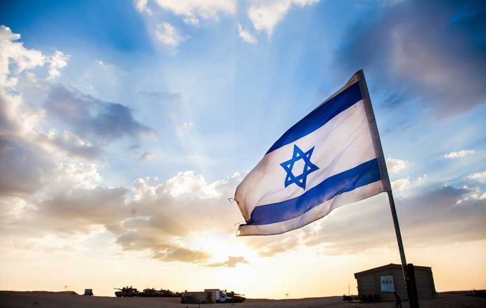 Israeli flag waving against a sunset backdrop with clouds