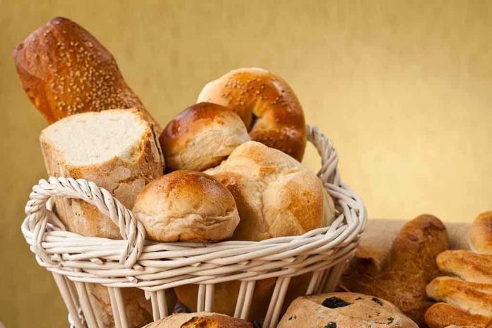 A basket filled with various types of fresh bread and rolls against a golden background